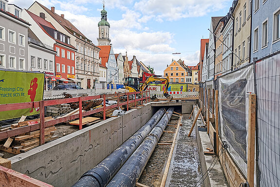Bauarbeiten zur Sanierung und Öffnung der Stadtmoosach in der Oberen Hauptstraße. Links an der Ufermauer zu sehen sind die Aussparungen für die Fischreliefs, die aus glänzend blauem Glasmosaik gestaltet werden. (Foto: Stadt Freising)