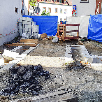 Einmündung zur Sackgasse: Die in einem bauschonenden Verfahren tief ins Erdreich eingebrachten Bohrpfahlwände aus Beton sind hier nur mehr sichtbar als Betonstreifen. (Ende Juli 2020)