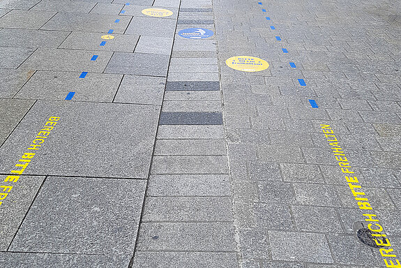 Mit gelben und blauen Markierungen wird darauf hingewiesen, dass die Entwässerungsrinne mit taktiler Kante sowie rechts und links jeweils 80 Zentimeter freibleiben müssen. (Foto: Stadt Freising)
