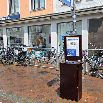 Die Baustellenzeitung ist zum Mitnehmen am Schiedereck (Bahnhofstraße/ Ecke Obere Hauptstraße) erhältlich. Im Hintergrund zu sehen die Litfaßsäule mit den neuen Plakatmotiven (Foto: Stadt Freising) 