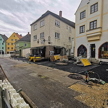 Links im Bild der fertige Pflasterstreifen entlang der Südfassaden - jetzt werden auch auf der Nordseite große Platten verlegt. (Foto: Stadt Freising)